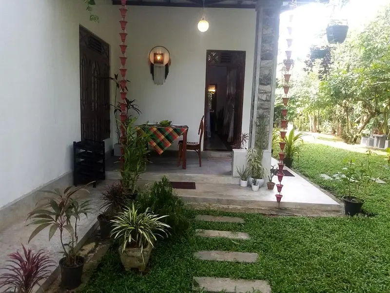 Shaded veranda with a seat and lantern, looking out over stepping stones and the green garden