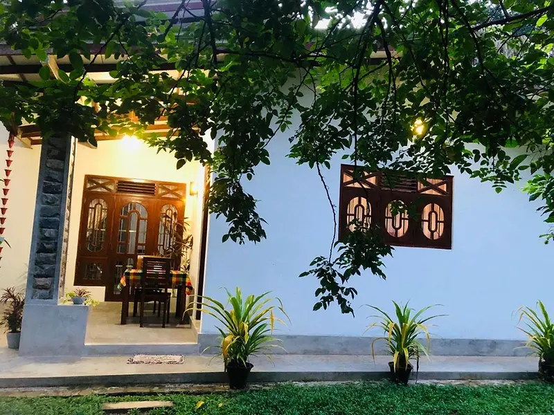 Villa Cozy guest house in Unawatuna: white walls and carved teak windows under the branches of a garden tree